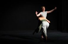 Two people dancing on a dark theatre stage