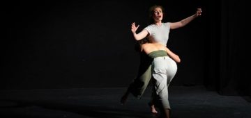 Two people dancing on a dark theatre stage
