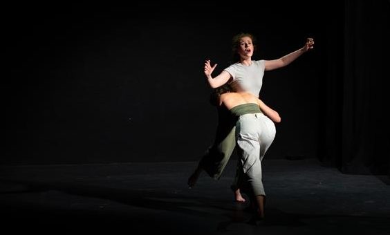 Two people dancing on a dark theatre stage
