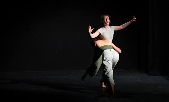 Two people dancing on a dark theatre stage